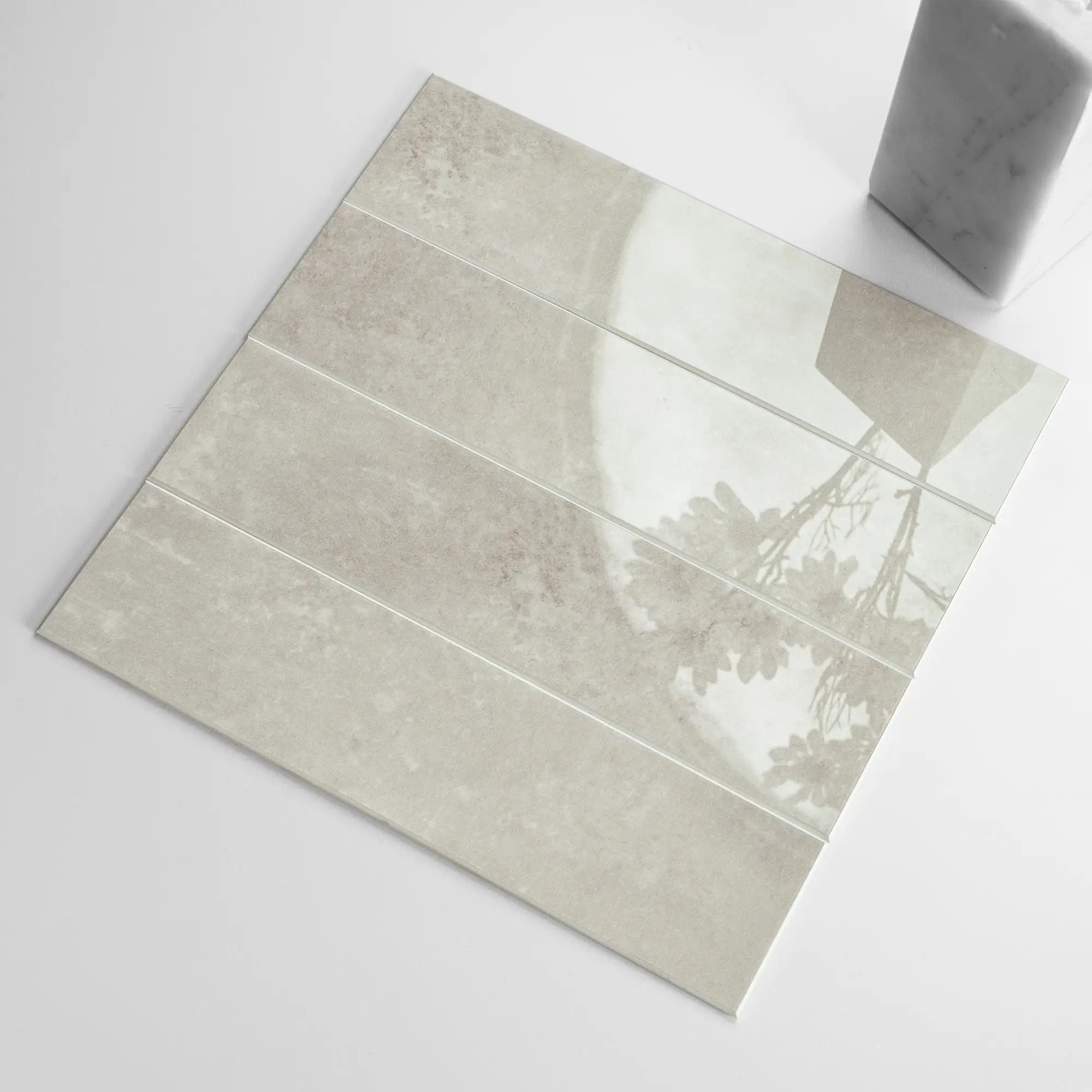 A glossy beige peel and stick backsplash tile with a subway design, showing the texture and thickness of the material.