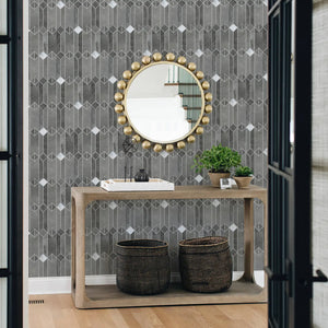 Gray mid-century geometric peel and stick backsplash tile behind a console table with decorative baskets and a round gold mirror in a modern entryway