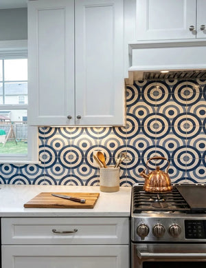 A renovated kitchen featuring Colamo Blue Ring glossy peel and stick backsplash, reflecting under-cabinet lighting behind a copper kettle.