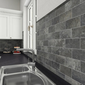 Charcoal gray stone peel and stick tiles installed as a kitchen backsplash.