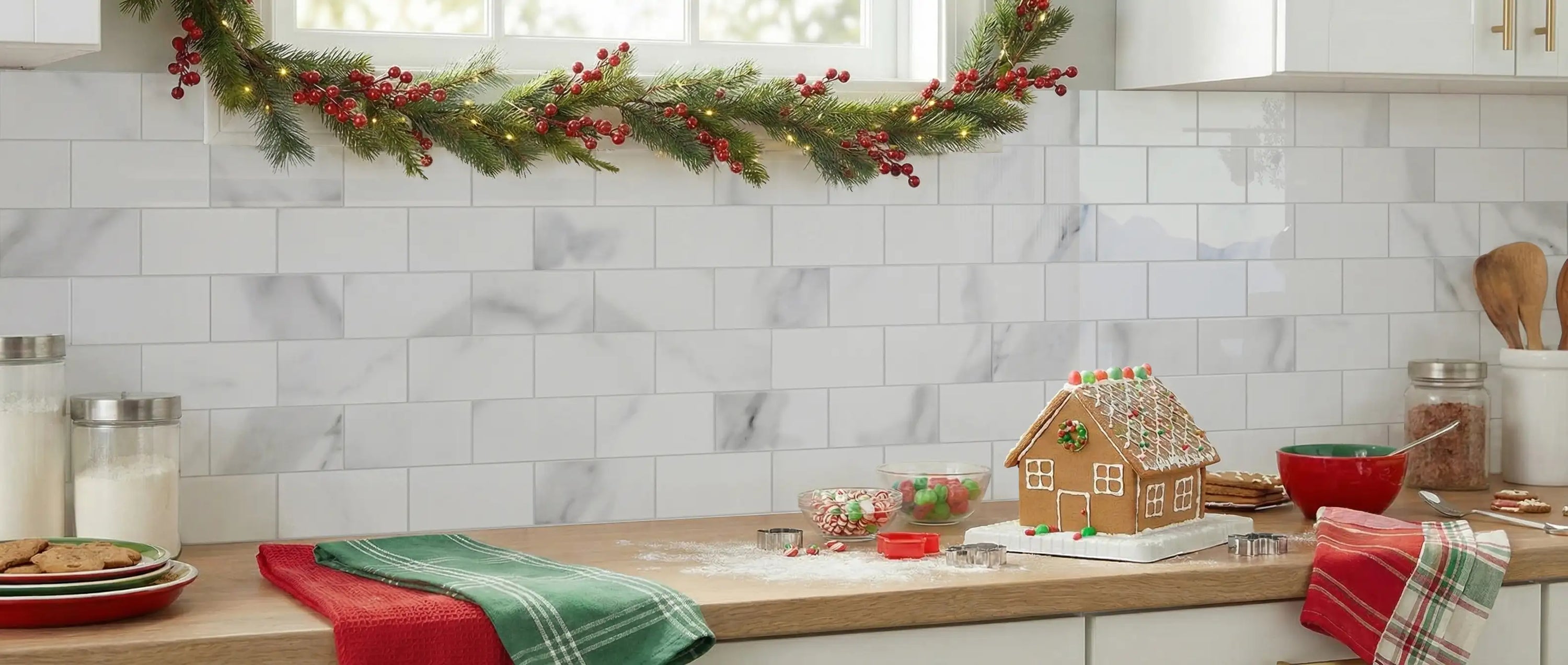 Carrara marble peel and stick subway tile backsplash in a festive kitchen setting with white shaker cabinets, butcher block countertops, and holiday garland decor.